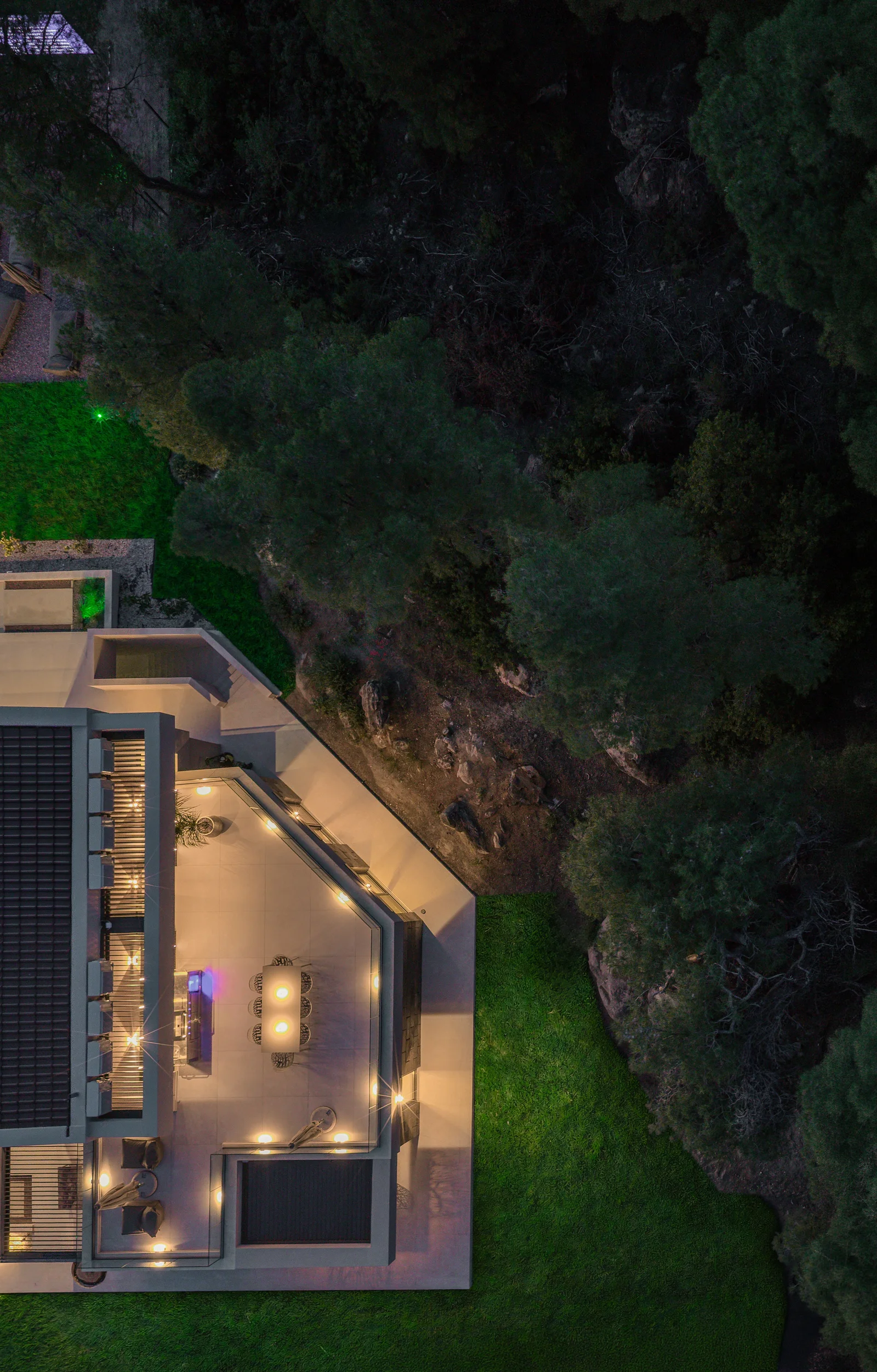 The estate seen from above at dusk, with the lit pool and the coast below